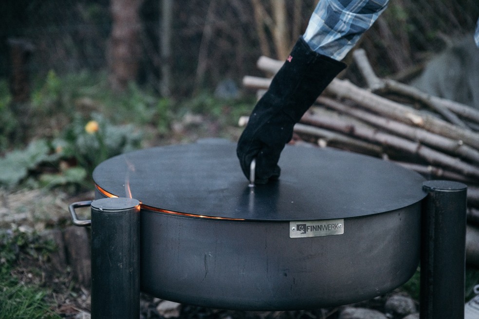 Deckel MATI beim Abdecken einer Feuerschale zum Ausglühen Gartenaufnahme
